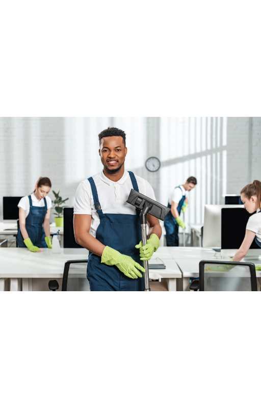 smiling african american cleaner holding vacuum cleaner brush near team of multicultural colleagues