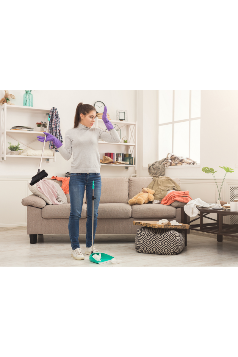 a woman standing in front of a sofa while cleaning the room