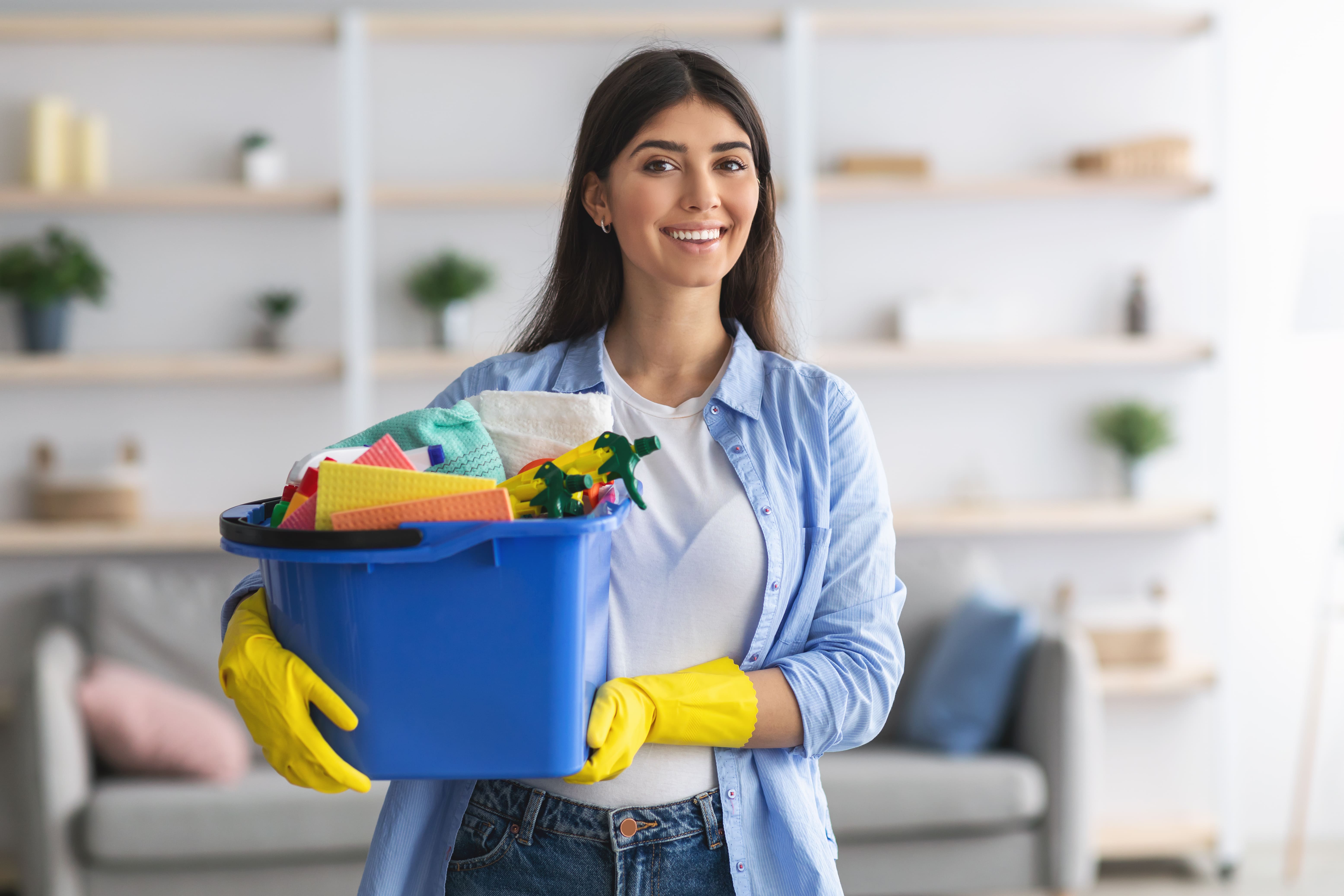 picture of a female cleaner carrying a bucket of cleaning supplies