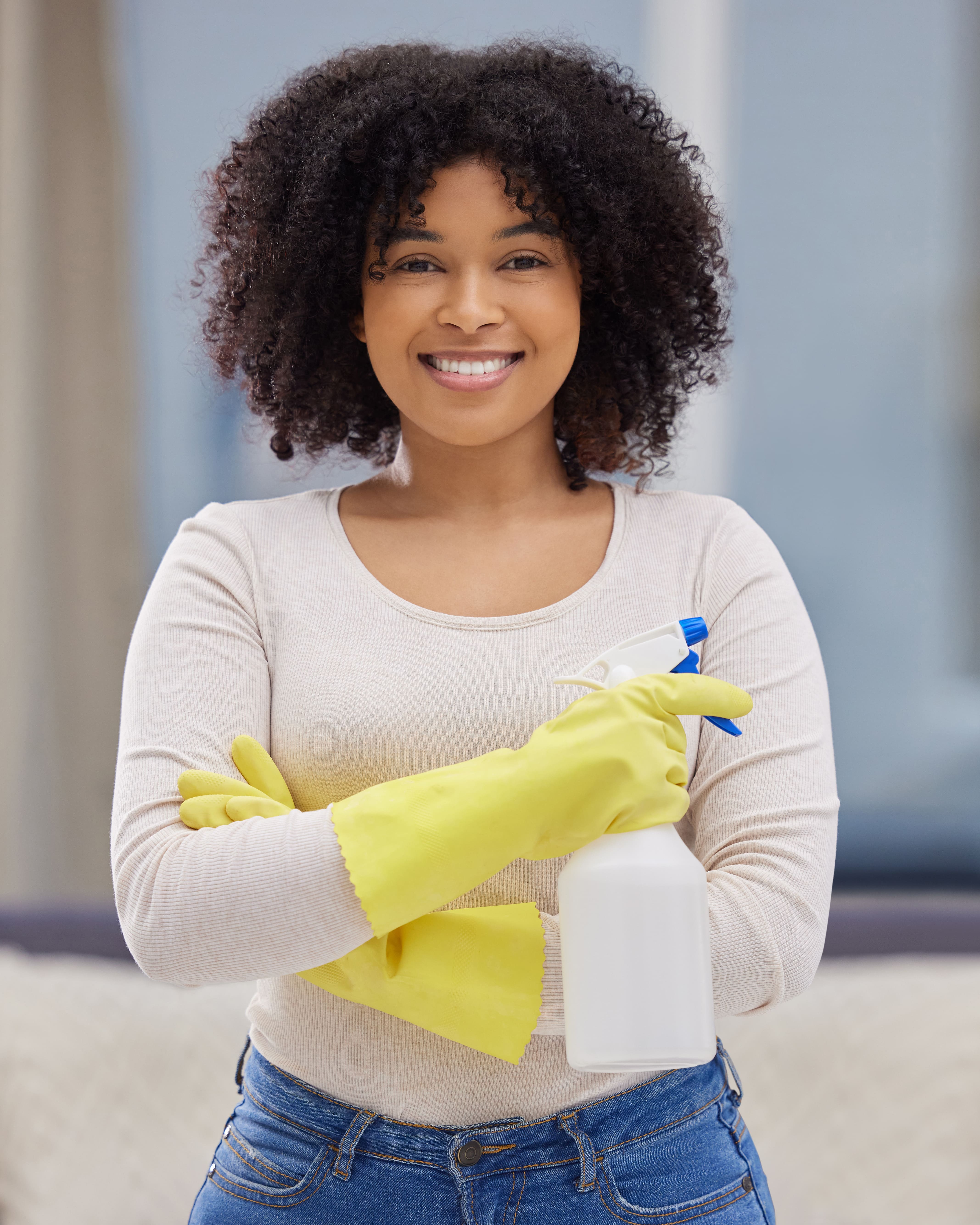 female cleaner holding cleaning supplies and smiling
